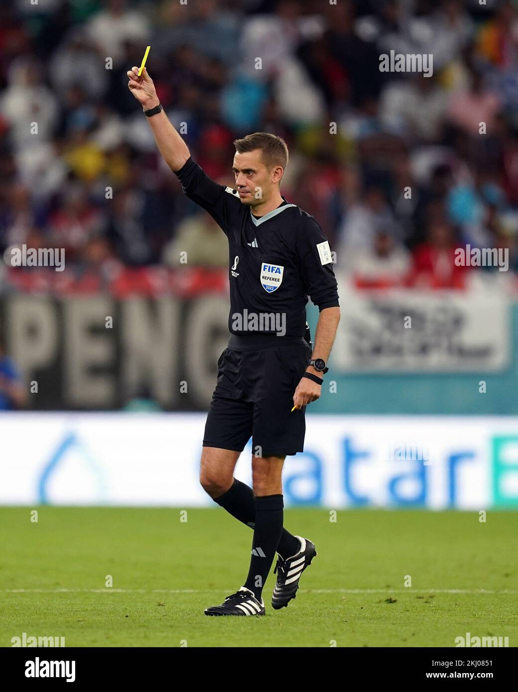 Referee Clement Turpin brandishes a yellow card during the FIFA World Cup Group H match at the Education City Stadium, Doha, Qatar. Picture date: Thursday November 24, 2022. Stock Photo
