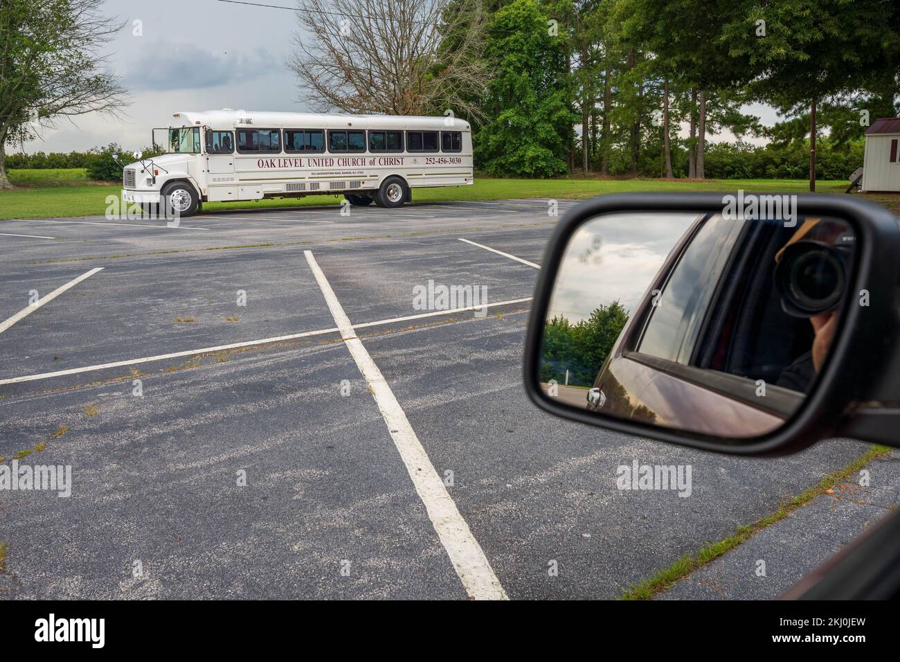 Photographer takes a picture of a white American church bus from his