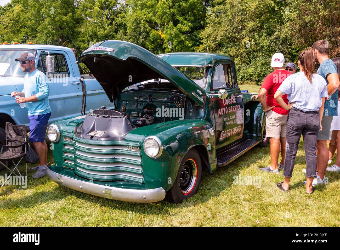 People gather around a classic green Chevrolet pick-up truck on display with the hood open at a car show in Fort Wayne, Indiana, USA. Stock Photo