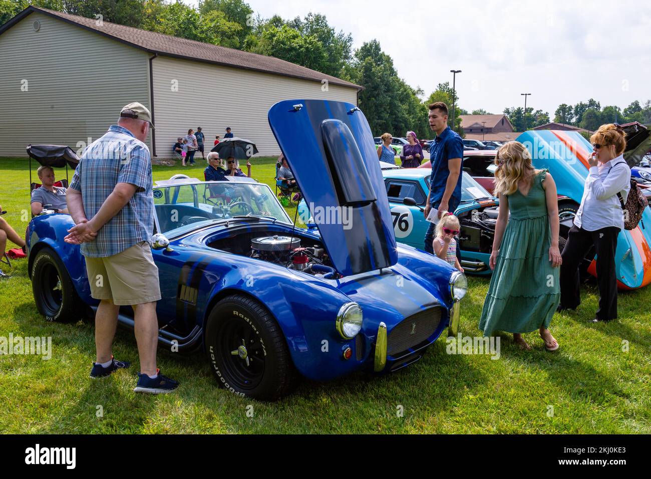 People inspect a blue AC Shelby Cobra 427 sports car replica on display