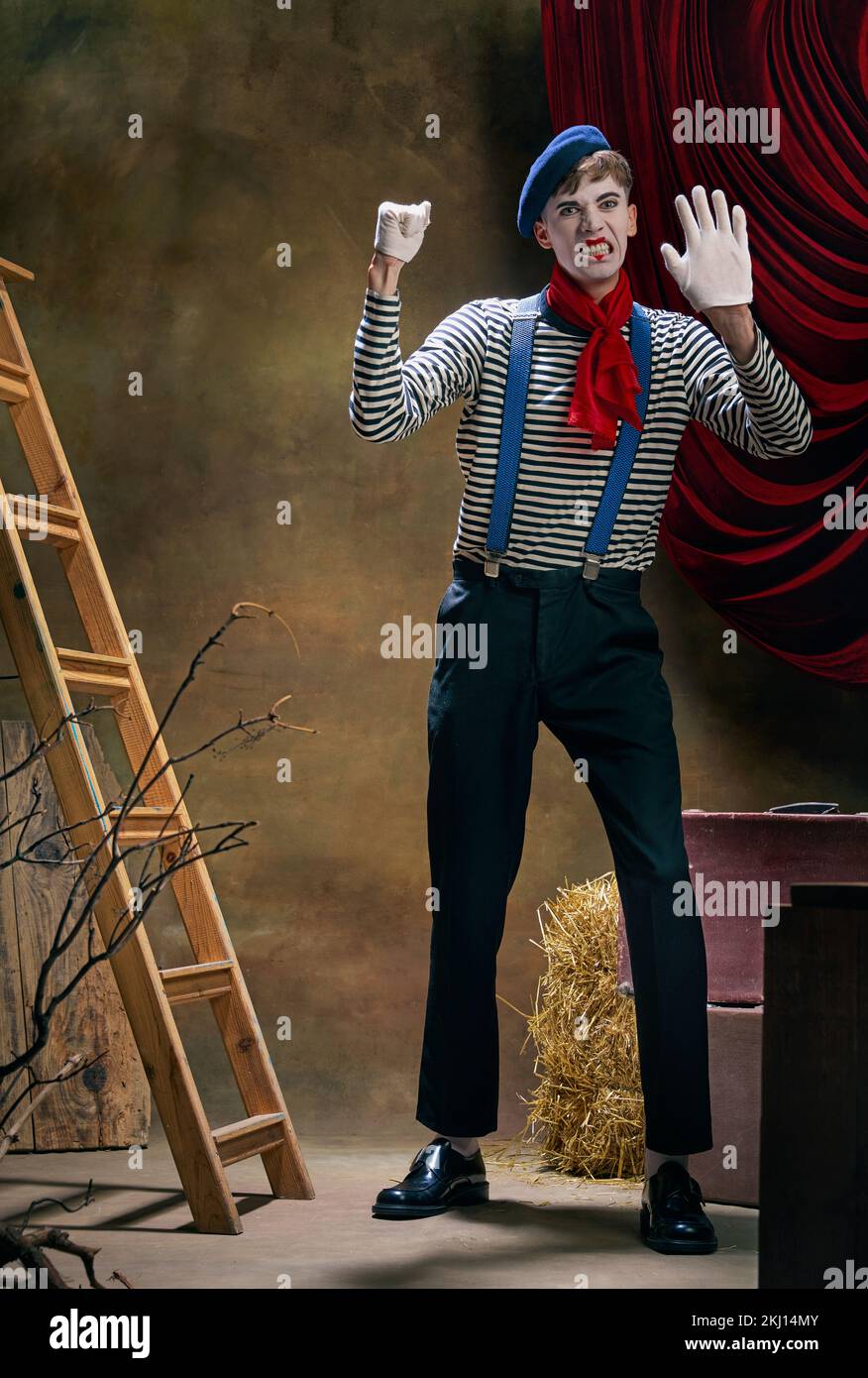 Portrait of male mime artist expressing sadness and loneliness over dark retro circus backstage background. Concept of human emotions, art, fashion Stock Photo