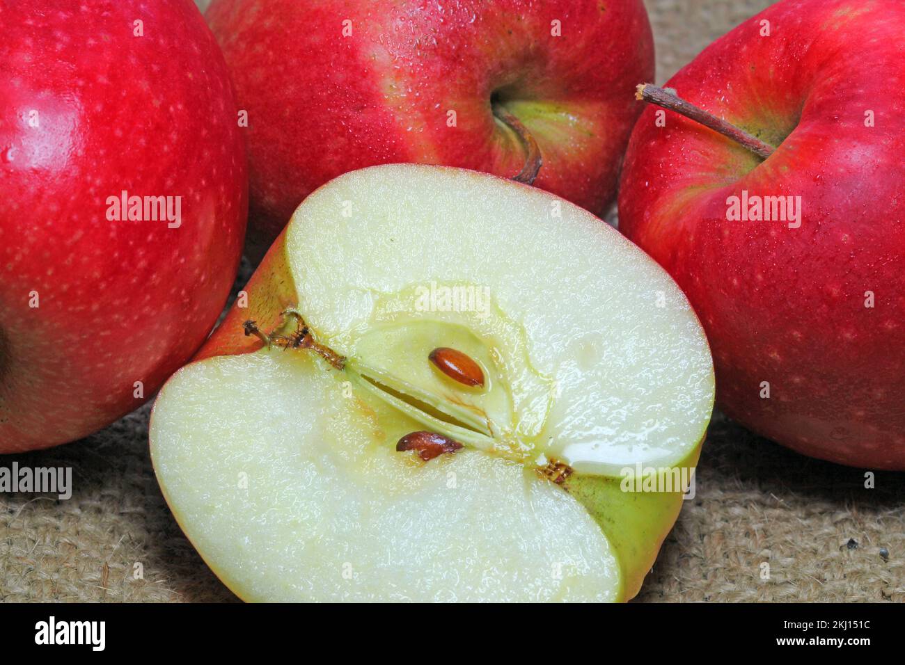 several red apples with one apple cut in half exposing the inside and