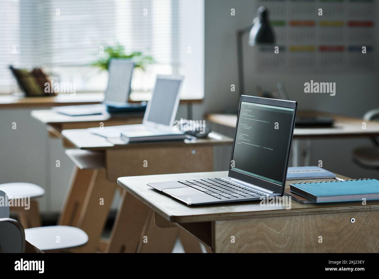 Computers with coding on screens standing on desks in class for studying IT technology Stock Photo