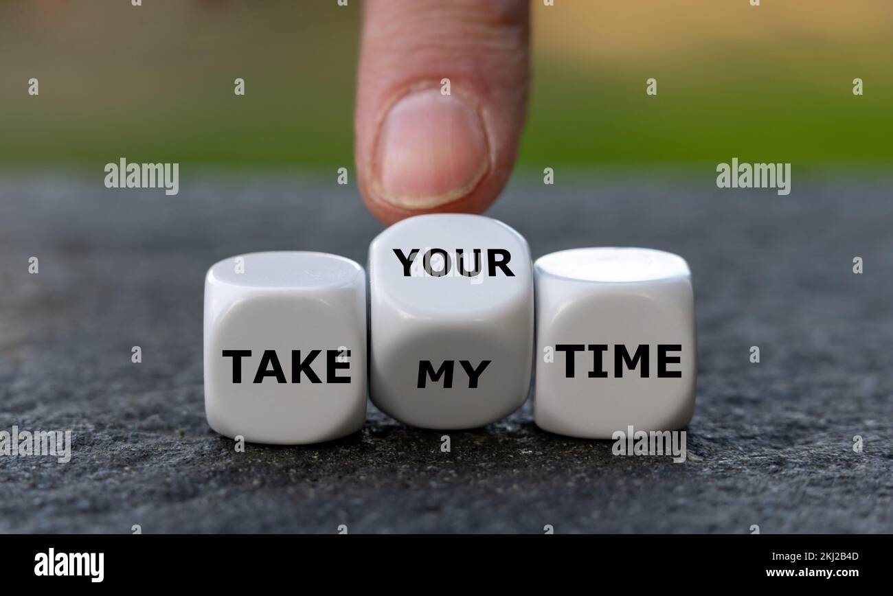 Hand turns dice and changes the expression 'take my time' to 'take your time'. Stock Photo