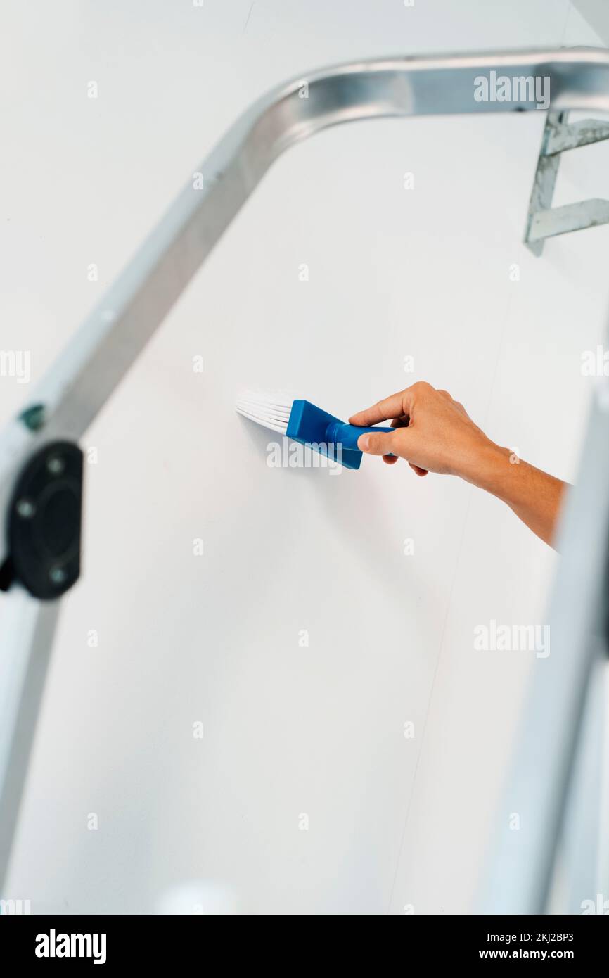 a young caucasian man spreads some glue with a brush on a white wall