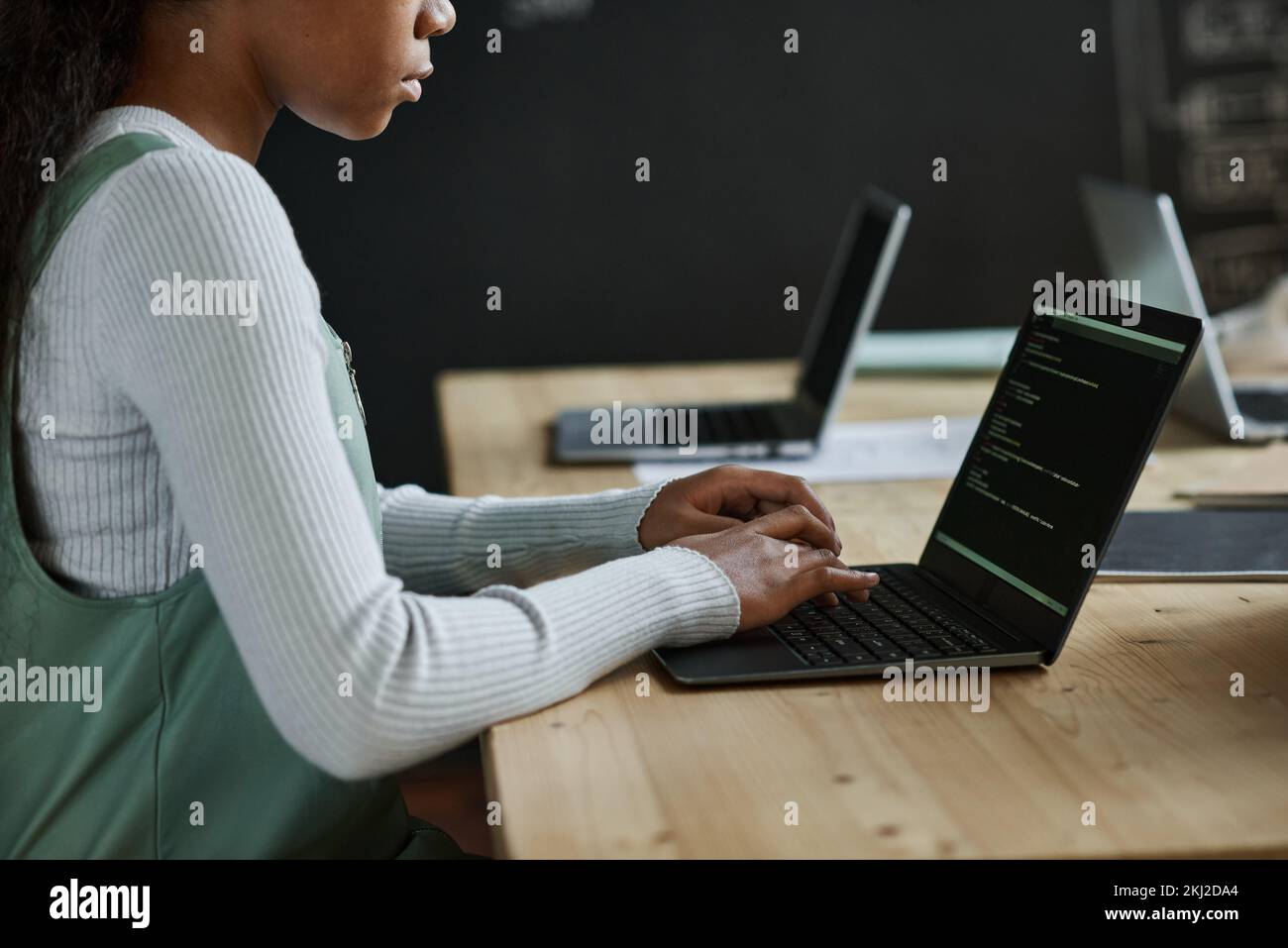 Close-up of african American schoolgirl sitting at table and typing codes on laptop at class Stock Photo