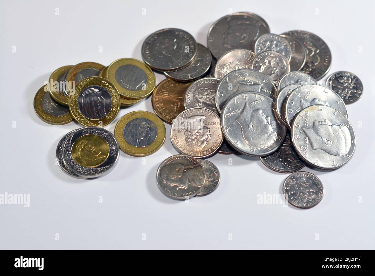 Pile of Saudi and American coins money of 1, 2 SAR one and two riyals, half a dollar 50 cents, 25 cents quarters, dime 10 cents and five cents, USA an Stock Photo