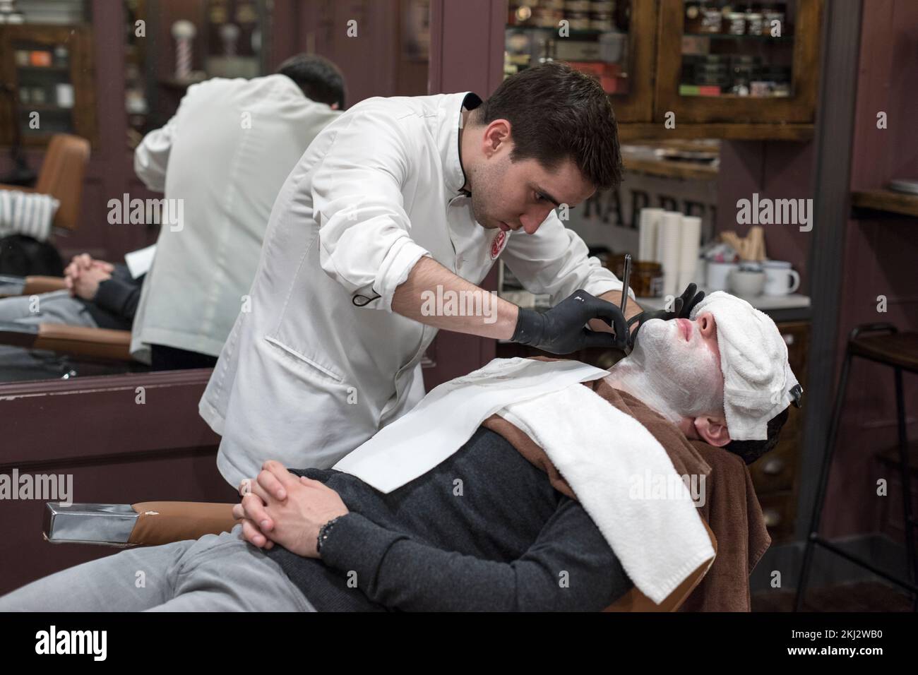 Ireland,Dublin, barber giving a straight razor shave to a customer