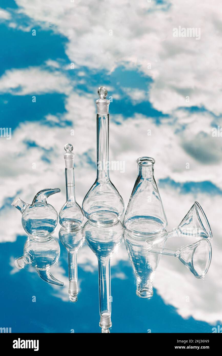 Various laboratory glassware on a mirror background with sky reflection. Conceptual laboratory testing and research of natural phenomena and resources Stock Photo