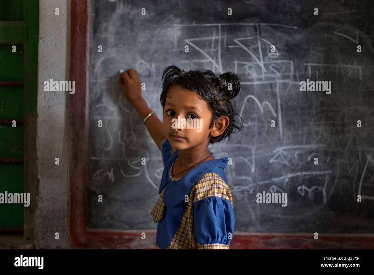 School girl writing on blackboard at school Stock Photo
