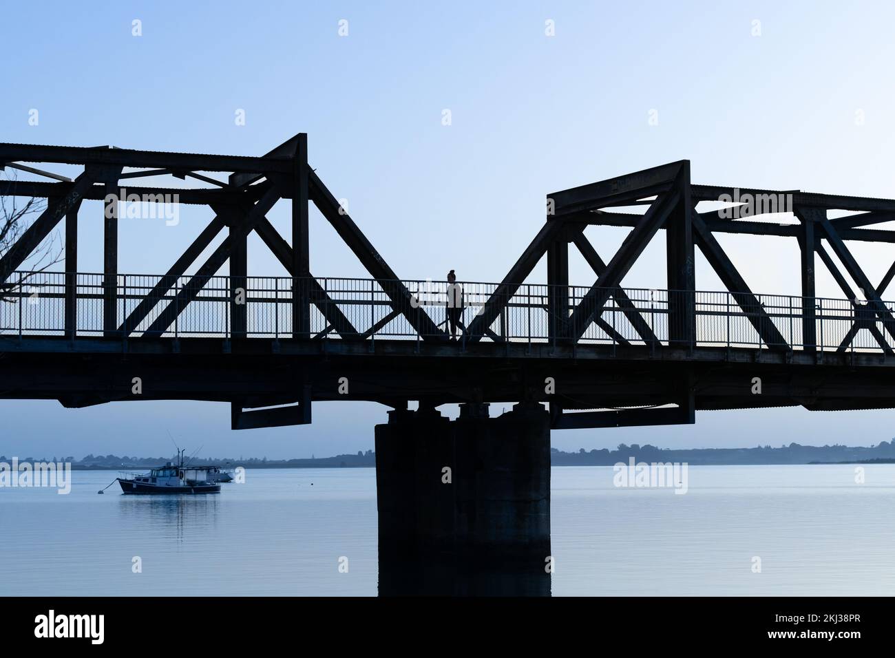 Tauranga morning back-lit effect image of railway bridge across Tauranga Harbour against blue. sky Stock Photo