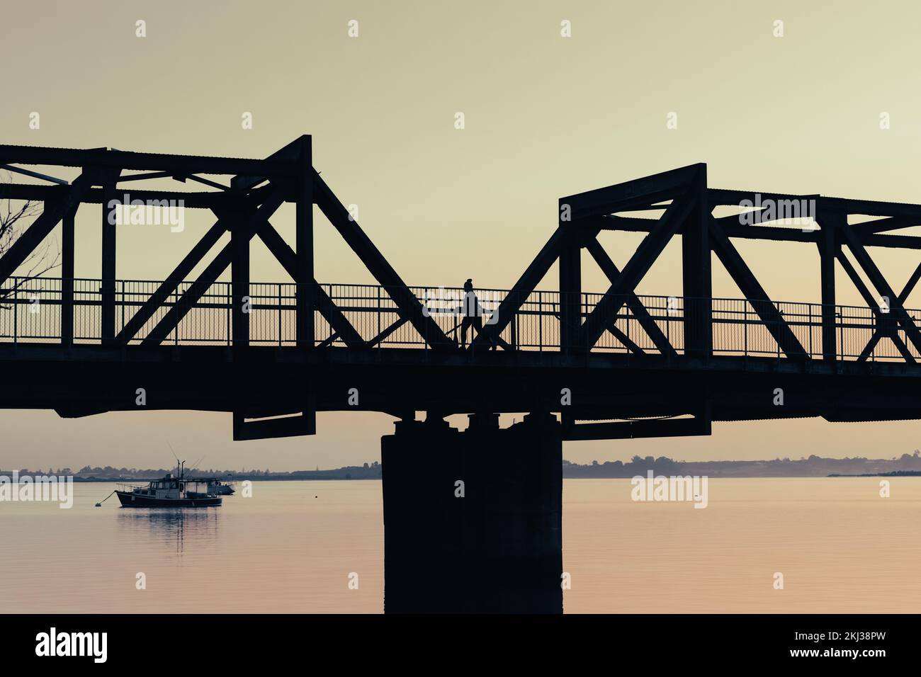 Tauranga morning alone on bridge walking for exercise over harbour back-lit by early morning light. Stock Photo