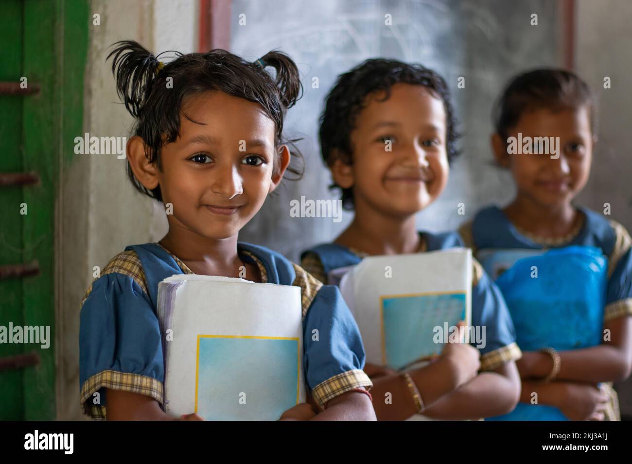Three School Children's holding books standing at school Stock Photo ...