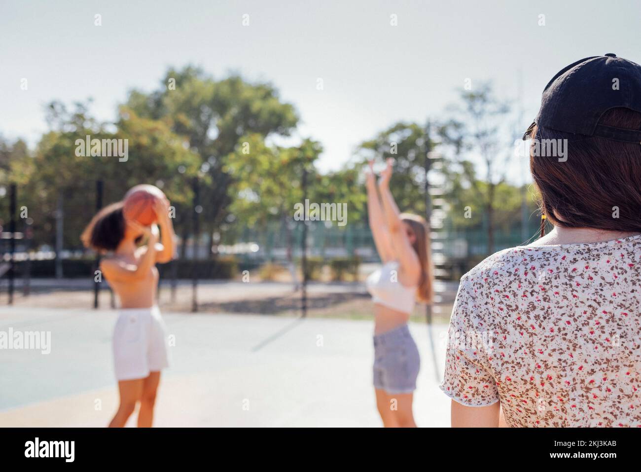 Multicultural group of young female friends bonding outdoors and having fun. Stylish cool teen girls gathering at basketball court, friends playing ba Stock Photo