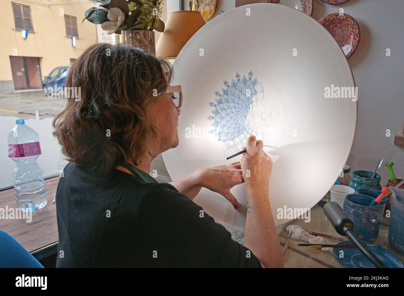 Decorator painting a ceramic plate in her workshop, Deruta village, Perugia, Umbria, Italy Stock Photo