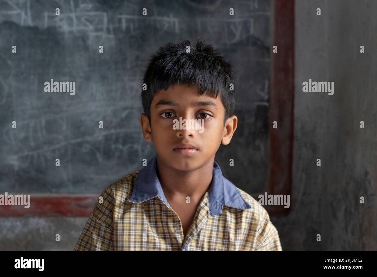 A Small School Boy Sitting in Classroom Stock Photo