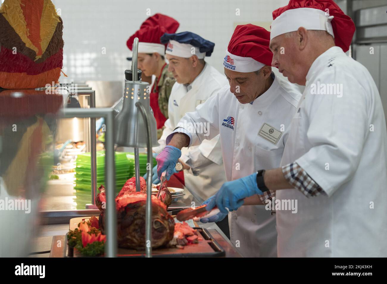 Fussa, Japan. 24th Nov, 2022. U.S. Ambassador to Japan Rahm Emanuel, 2nd right, and U.S. Air Force Lt. Gen. Ricky Rupp, right, Commander of Forces Japan, dressed in chefs uniforms, serve ham and turkey to service members during Thanksgiving at the Samurai Cafe Dining Facility at Yokota Air Base, November 24, 2022 in Fussa, Japan. Credit: TSgt. Christopher Hubenthal/US Air Force/Alamy Live News Stock Photo