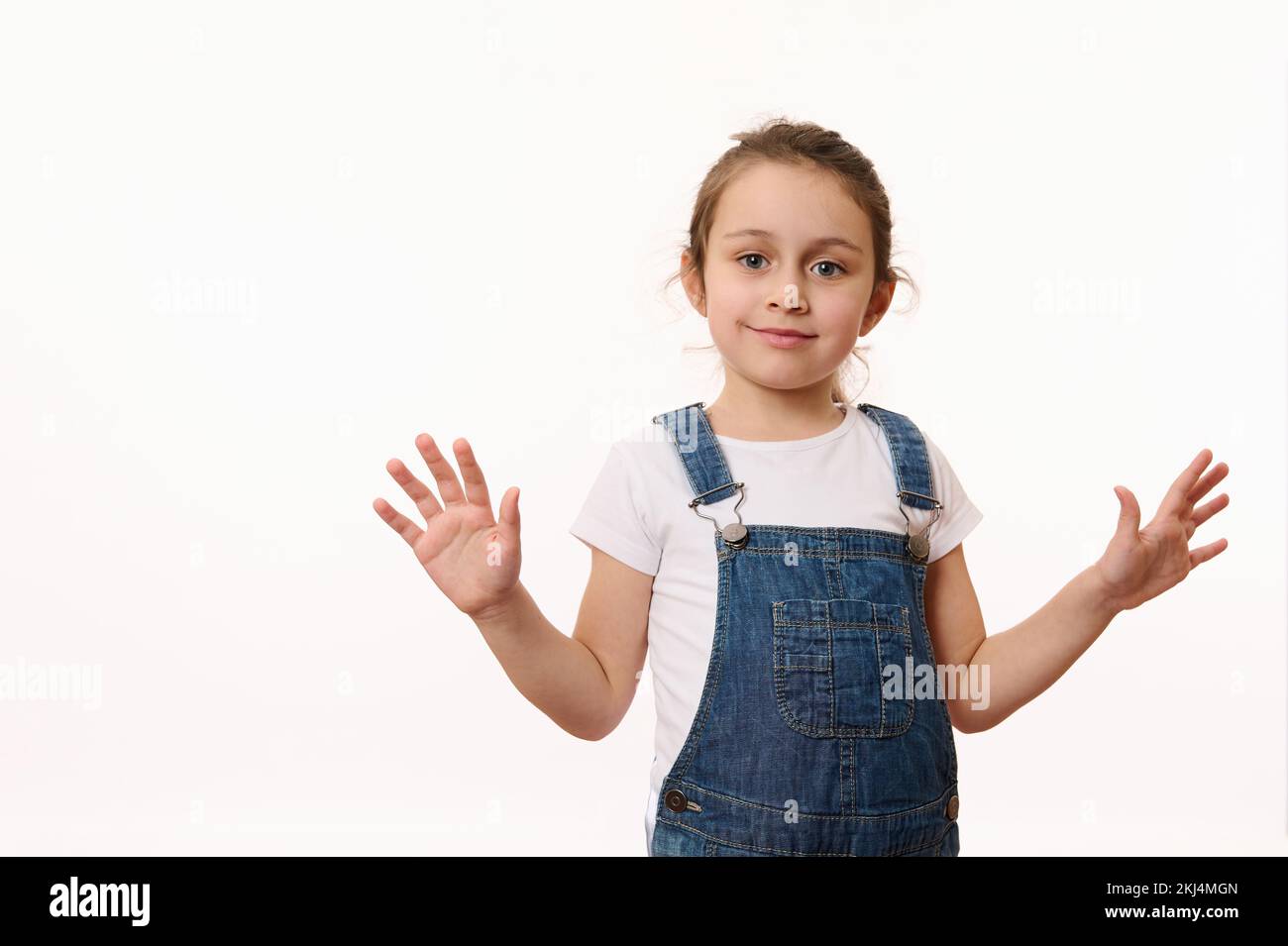 Emotional portrait of a cute baby girl, wearing blue denim overalls