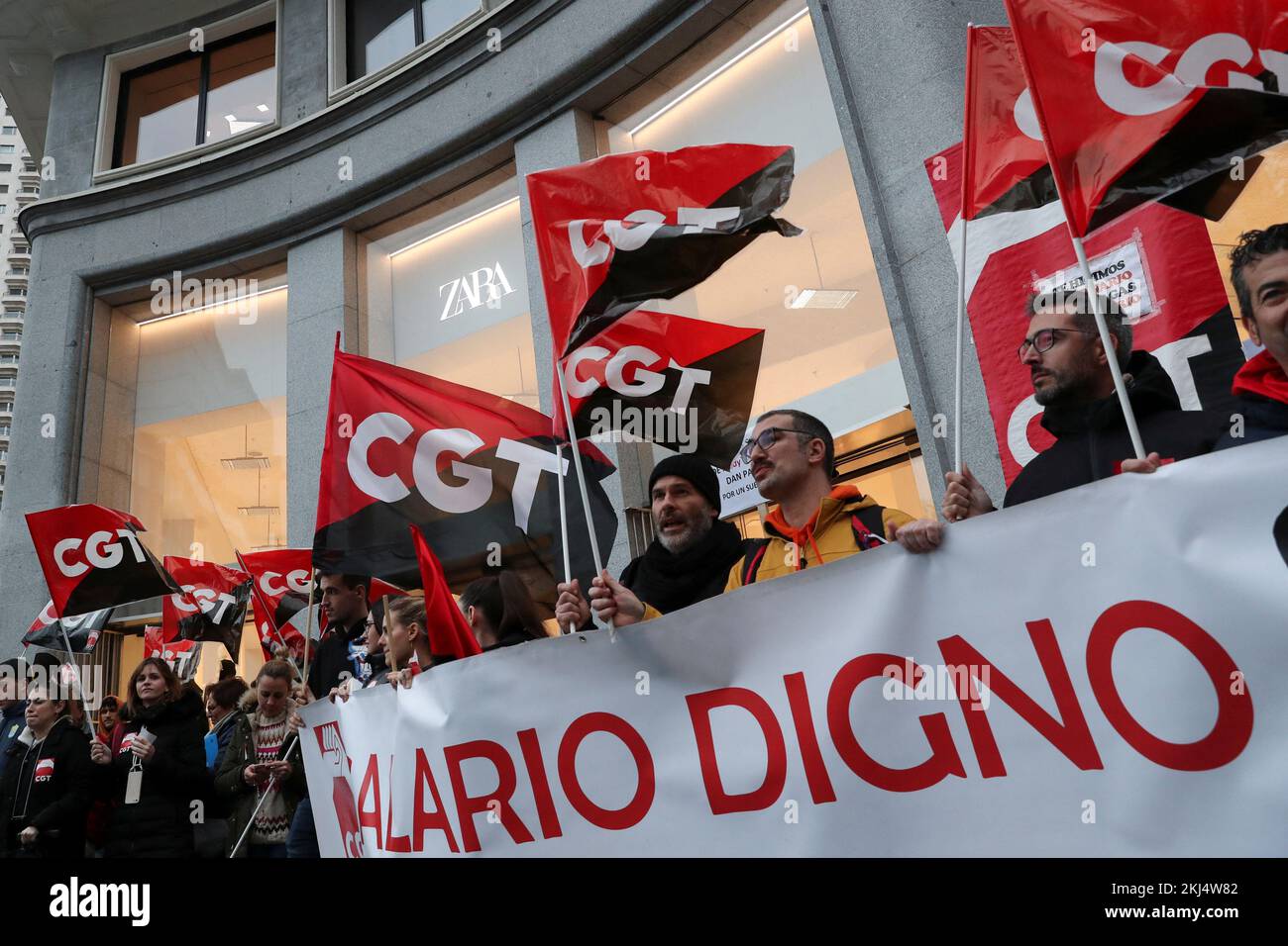 People hold flags from Spain's CGT labour union as they protest outside a  Zara clothing store, an Inditex brand, for an increase in salaries amidst  inflation hikes, in Madrid, Spain, November 24,