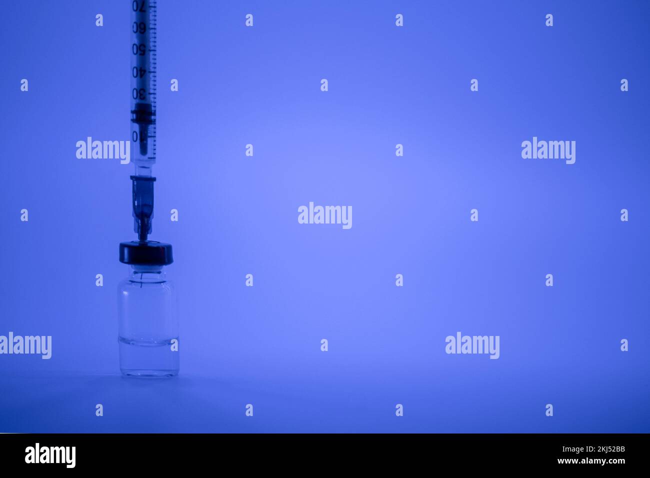 Vaccine vial, syringe with flu shot needle, vaccination medical concept, subcutaneous injection on blue background. Copy space. Test immunization and Stock Photo