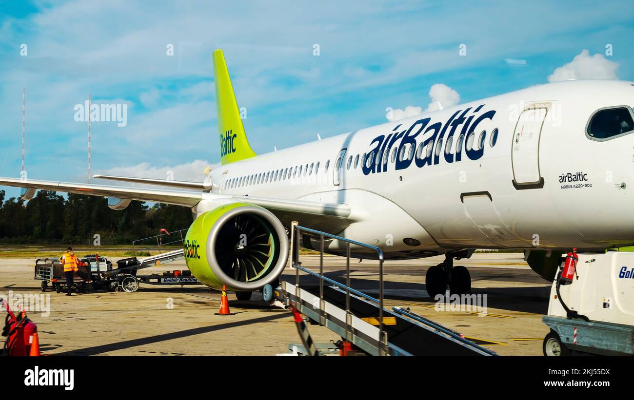Kerkyra, Greece - 09 29 2022: View of Corfu Airport On Green Plane of AirBaltic. Parking Lot For Aircraft, Aircraft Is Loaded With Luggage Before Stock Photo