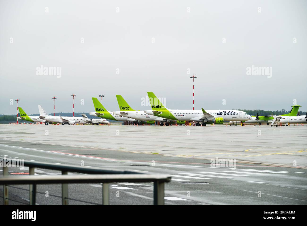 Riga, Latvia - 09 29 2022: View of Riga Airport On Green Planes of AirBaltic. Parking Lot For Aircraft, Against Backdrop Of Cloudy Weather. Stock Photo