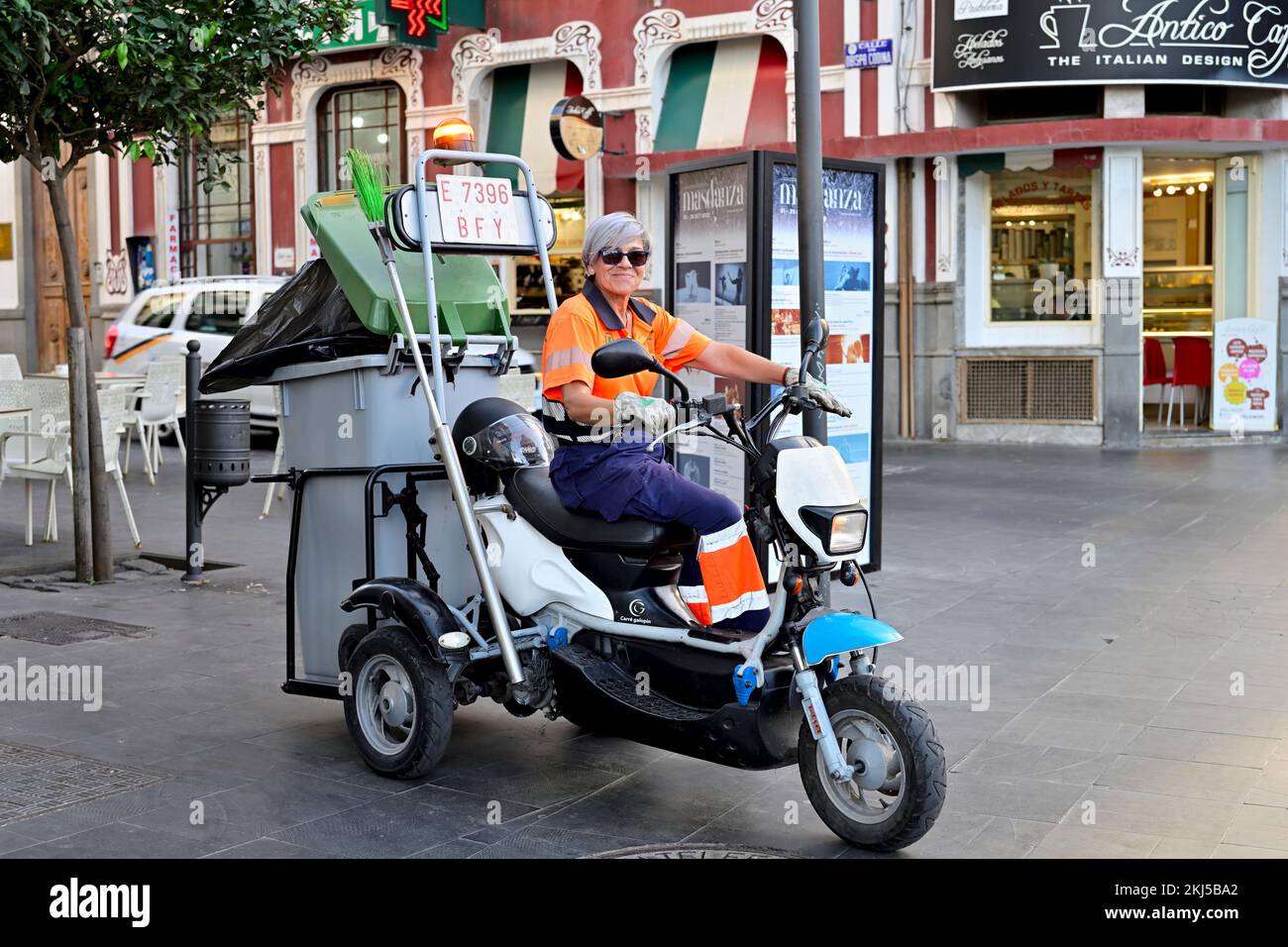 Woman street sweeper on motorcycle trike with broom and rubbish bin in pedestrianized shopping street of  Calle Triana, Las Palmas, Gran Canaria Stock Photo