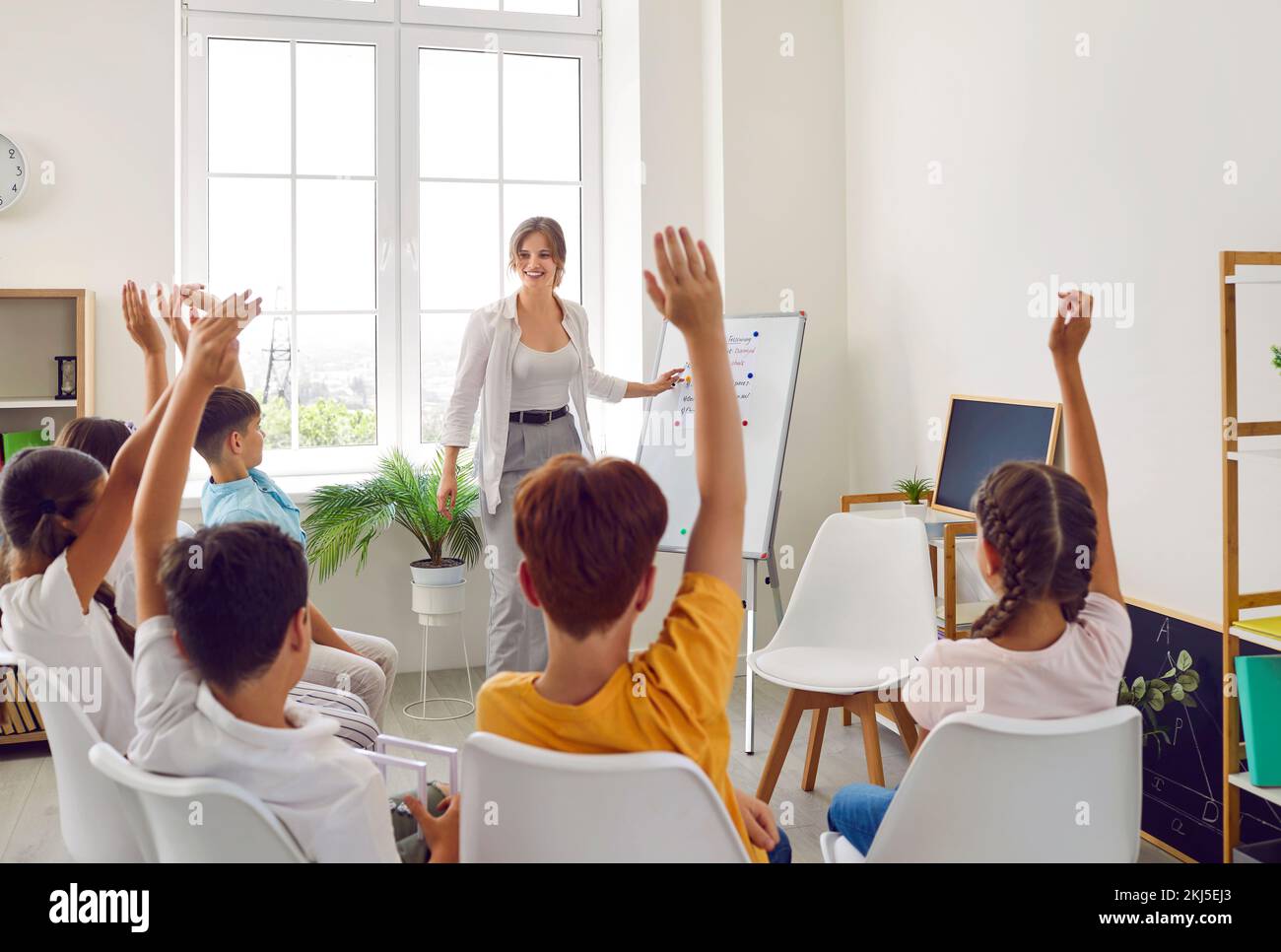 Selective focus on hand. Children or Schoolkids or students raising hands up with teacher. Stock Photo