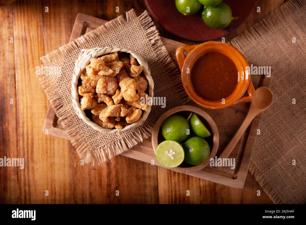 Chicharrones. Deep fried pork rinds, crispy pork skin pieces, traditional mexican ingredient or snack served with lemon juice and red hot chili sauce. Stock Photo