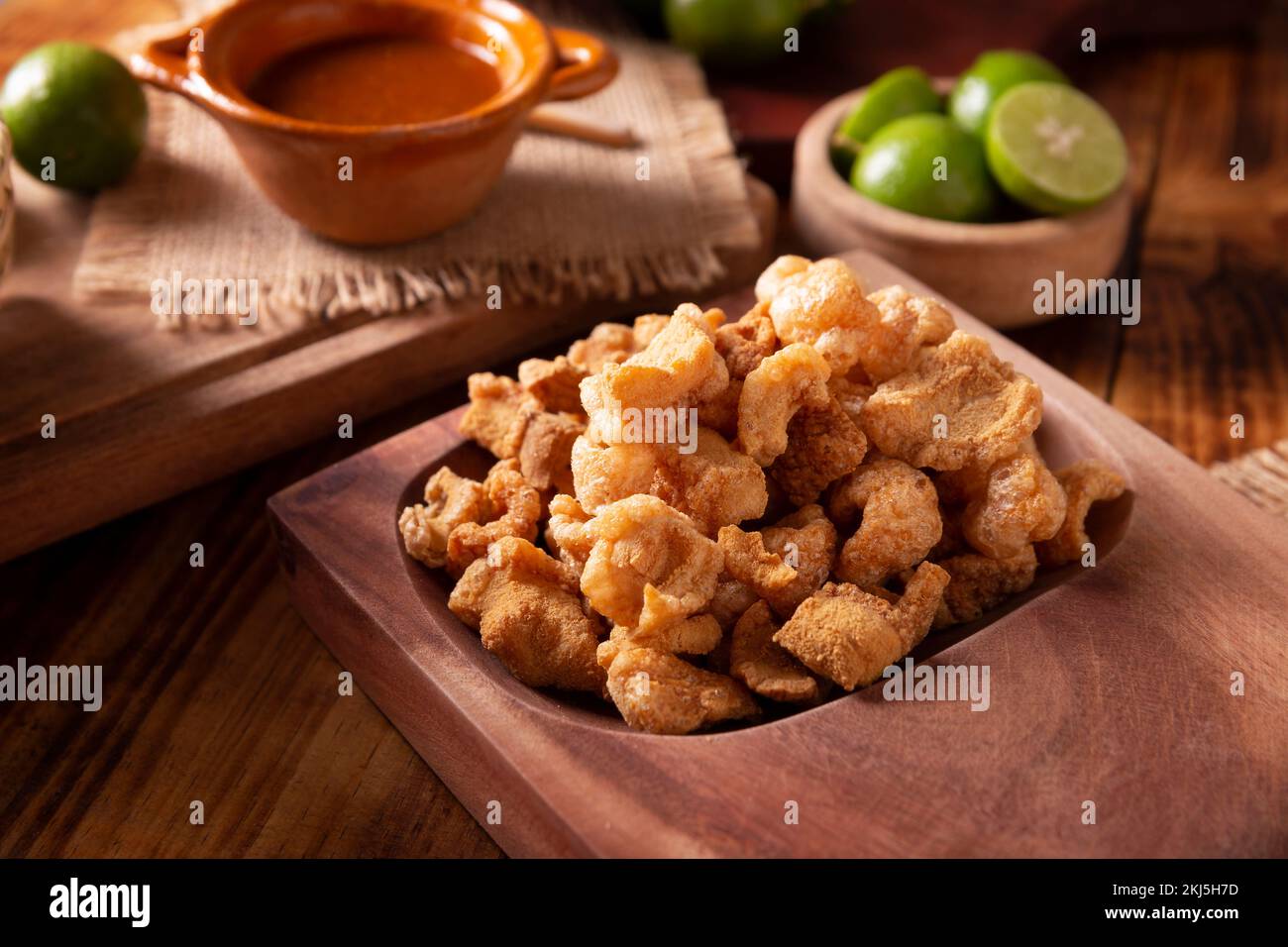 Chicharrones. Deep fried pork rinds, crispy pork skin pieces, traditional mexican ingredient or snack served with lemon juice and red hot chili sauce. Stock Photo