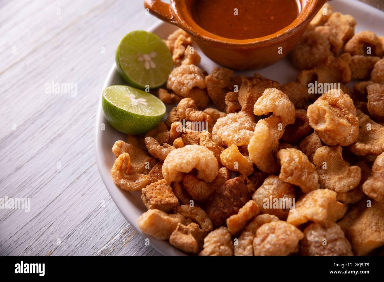 Chicharrones. Deep fried pork rinds, crispy pork skin pieces, traditional mexican ingredient or snack served with lemon juice and red hot chili sauce. Stock Photo