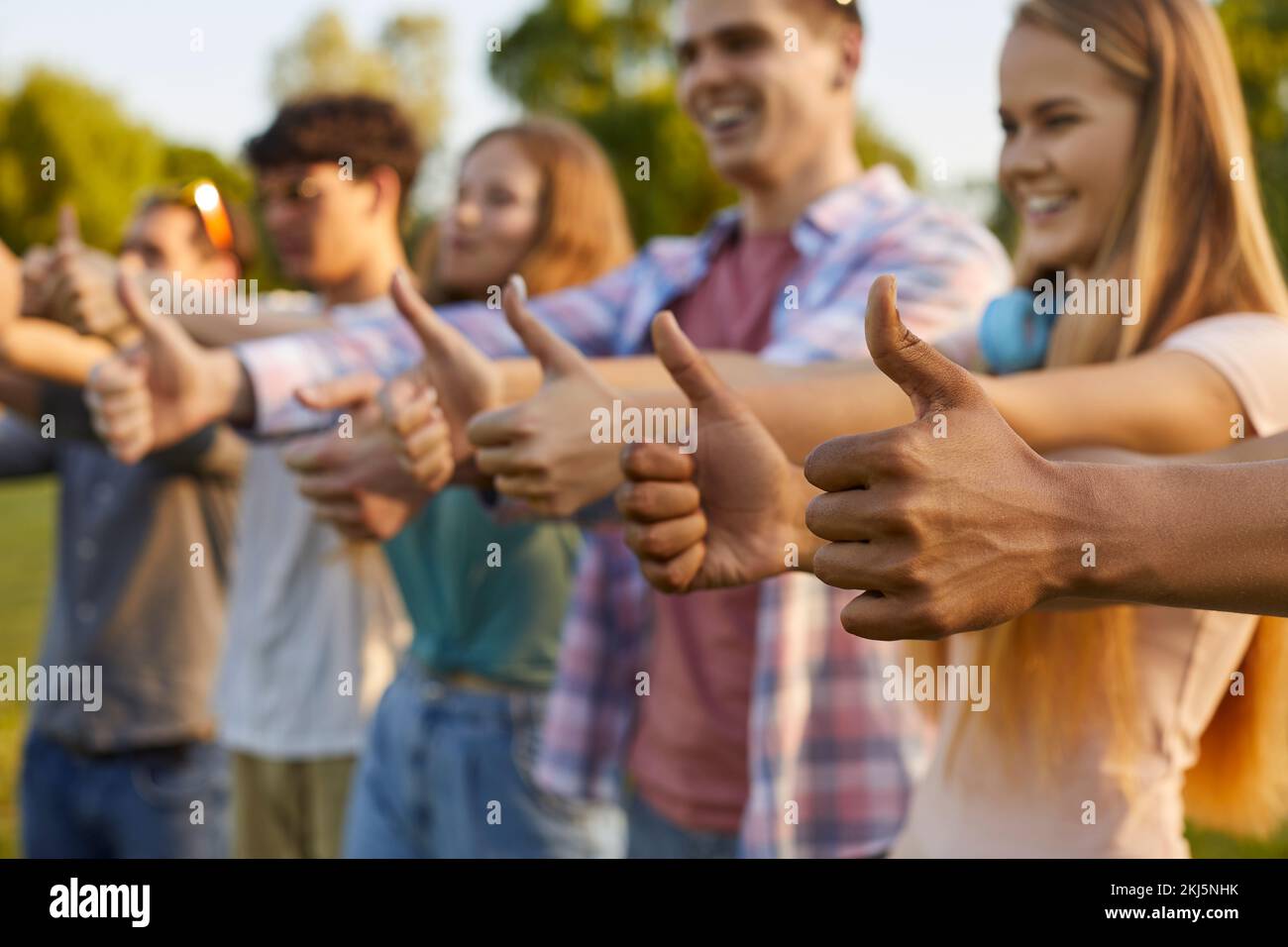Diverse group of happy men and women doing thumbs up gestures at summer festival Stock Photo