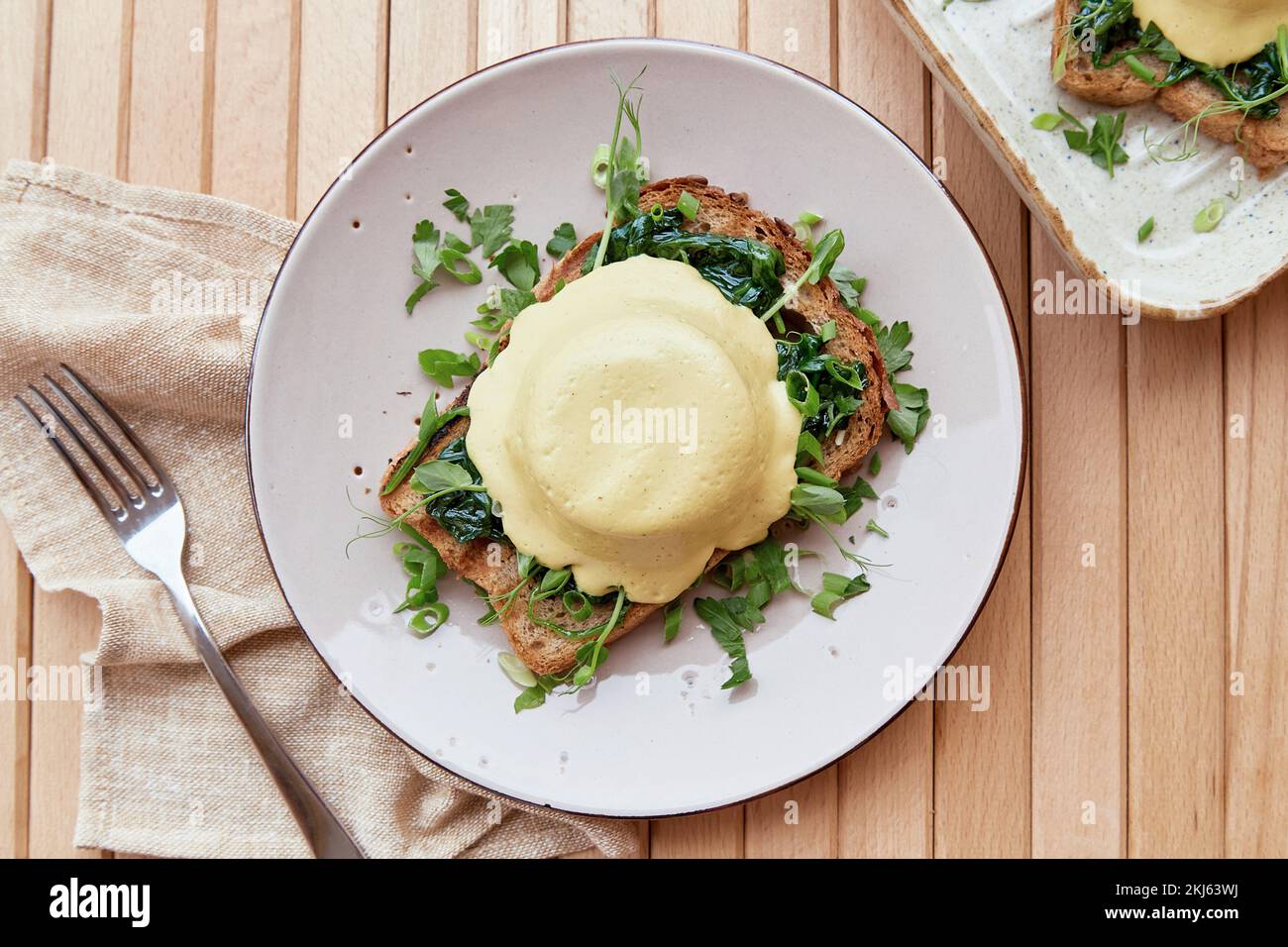 Vegan eggs benedict dish with sourdough bread, creamy plantbased
