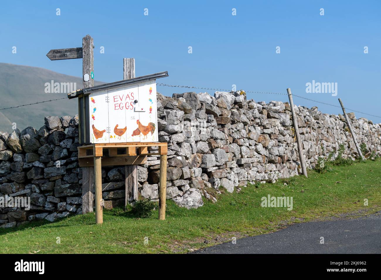 Farmer selling Free Range Eggs from an honesty box at the end of a farm lane. Cumbria, UK. Stock Photo