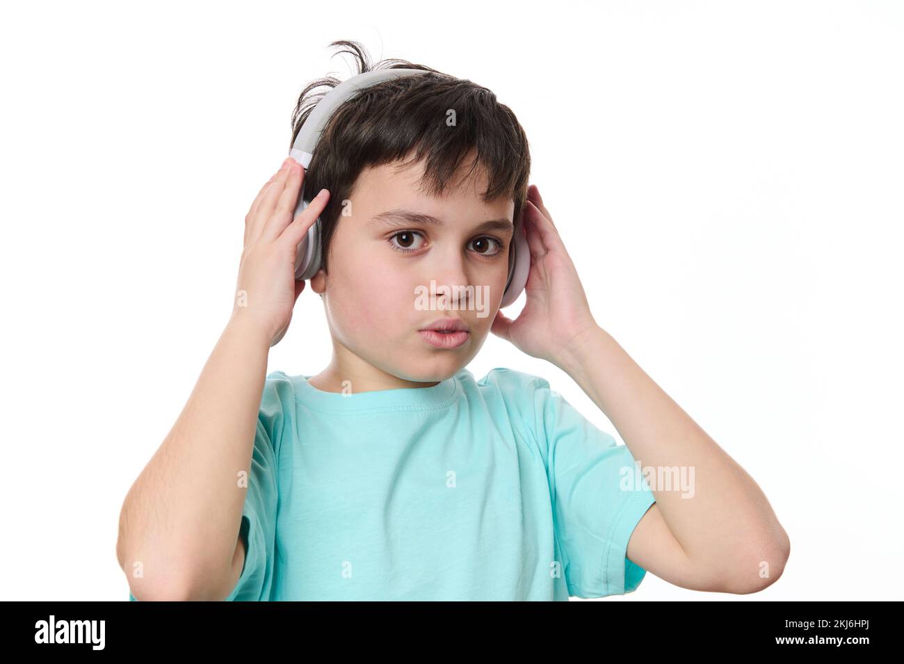 Closeup of a happy cute teenage boy puts on wireless stereo headphones