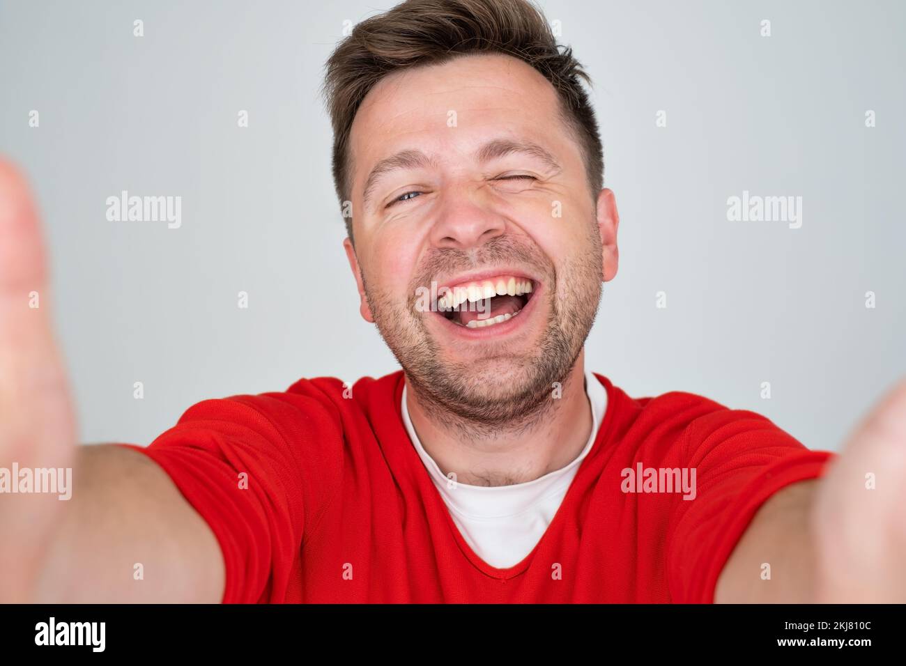 Handsome young man makes self, smiling broadly, on a gray background Stock Photo