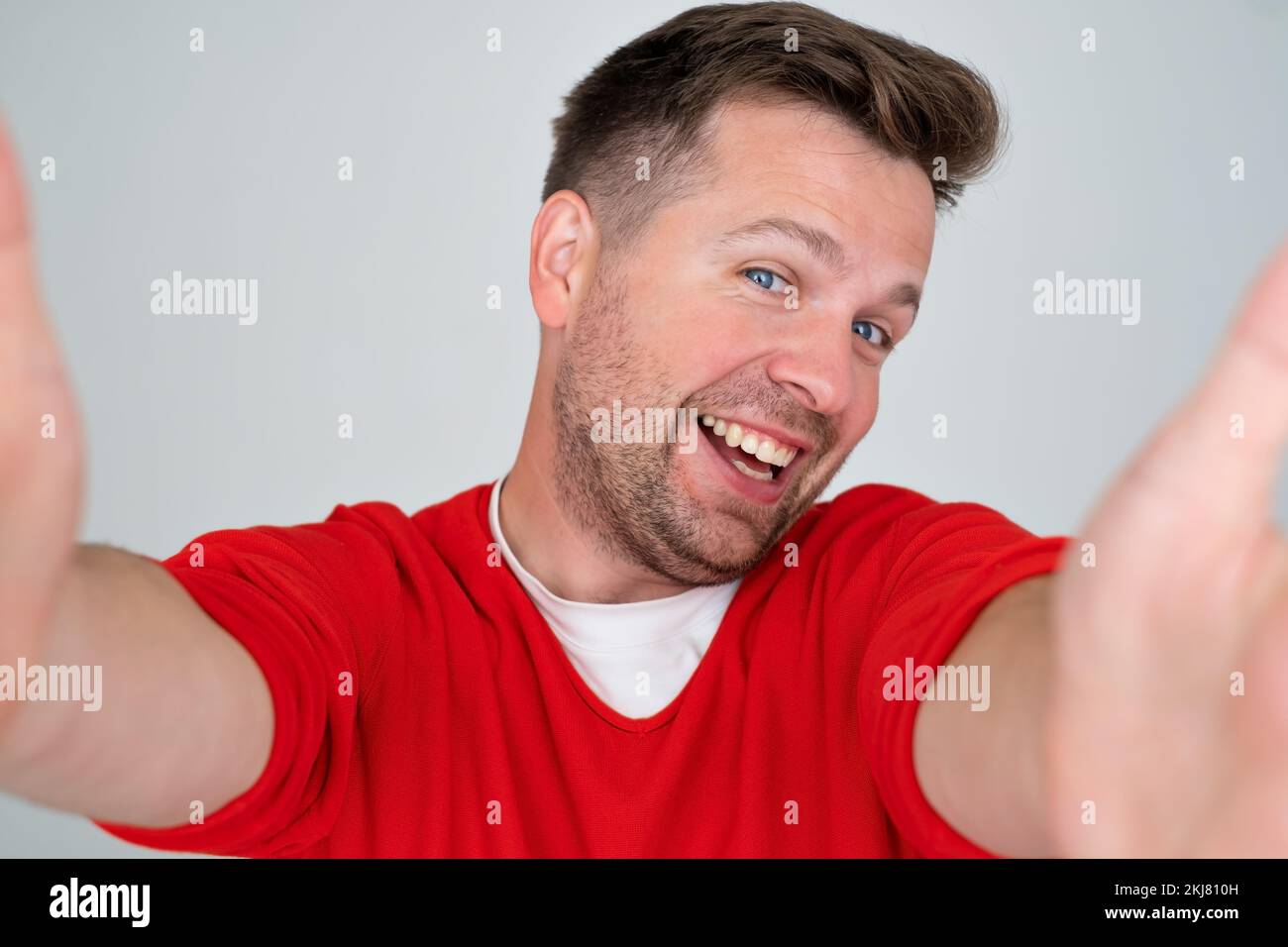 Handsome young man makes self, smiling broadly, on a gray background Stock Photo