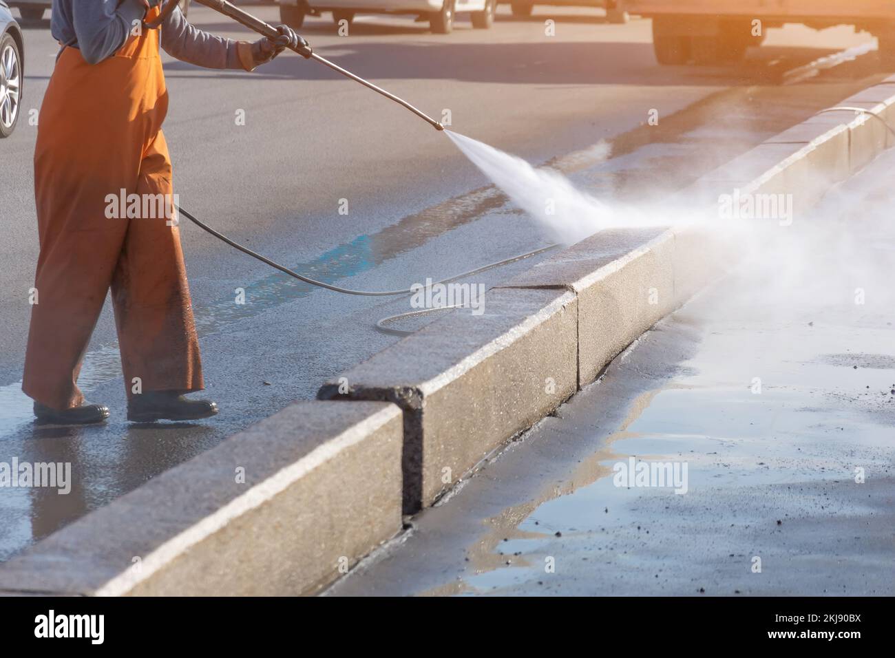 Worker cleaning driveway with gasoline high pressure washer splashing