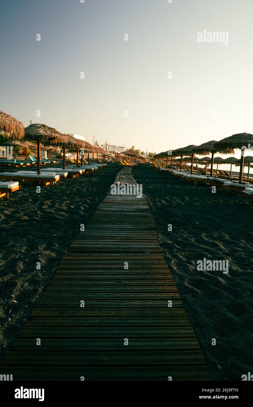 Seascape and Chaise lounges black beach of Kamari in Santorini Stock Photo