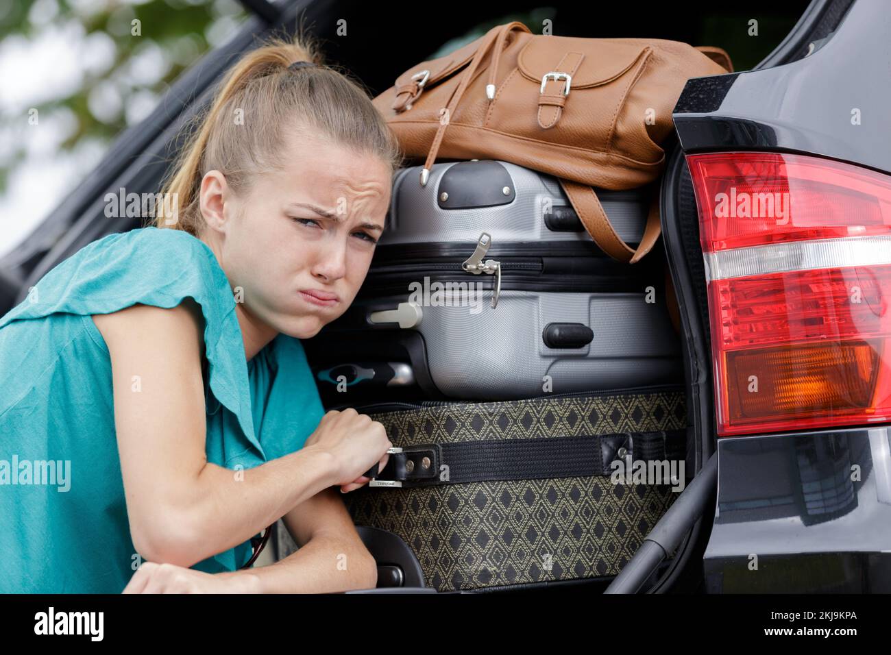 female pushing luggage in car trunk Stock Photo Alamy