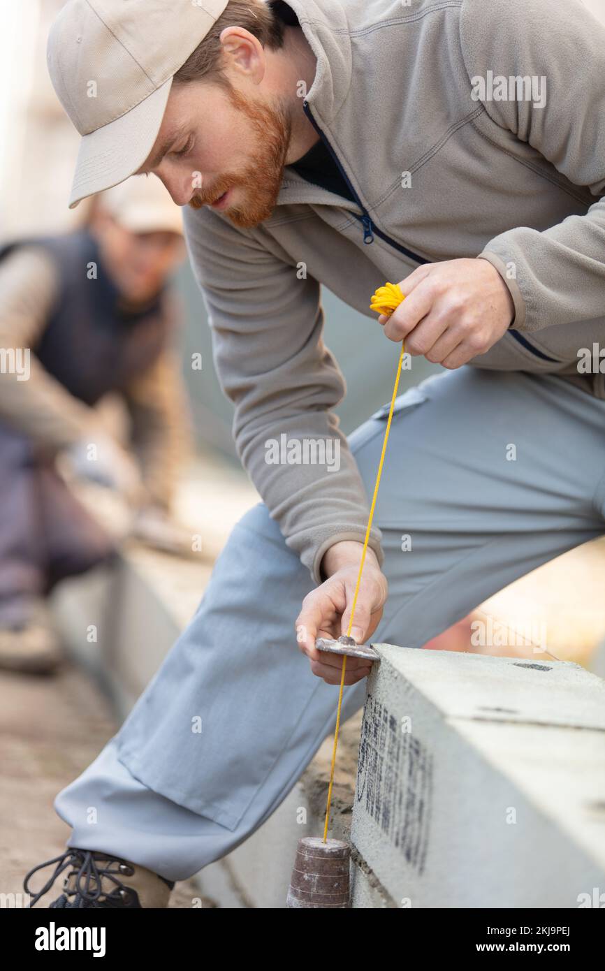 builder using plumb weight on construction site Stock Photo
