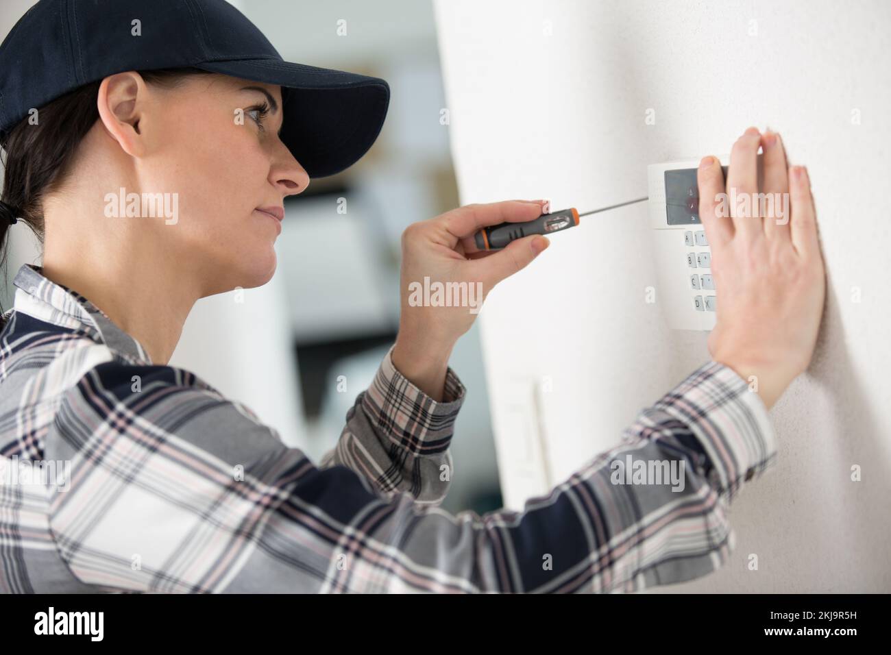 female technician installing security system using screwdriver Stock