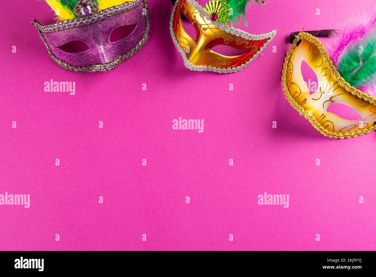 Composition of colourful mardi gras carnival masks on pink background