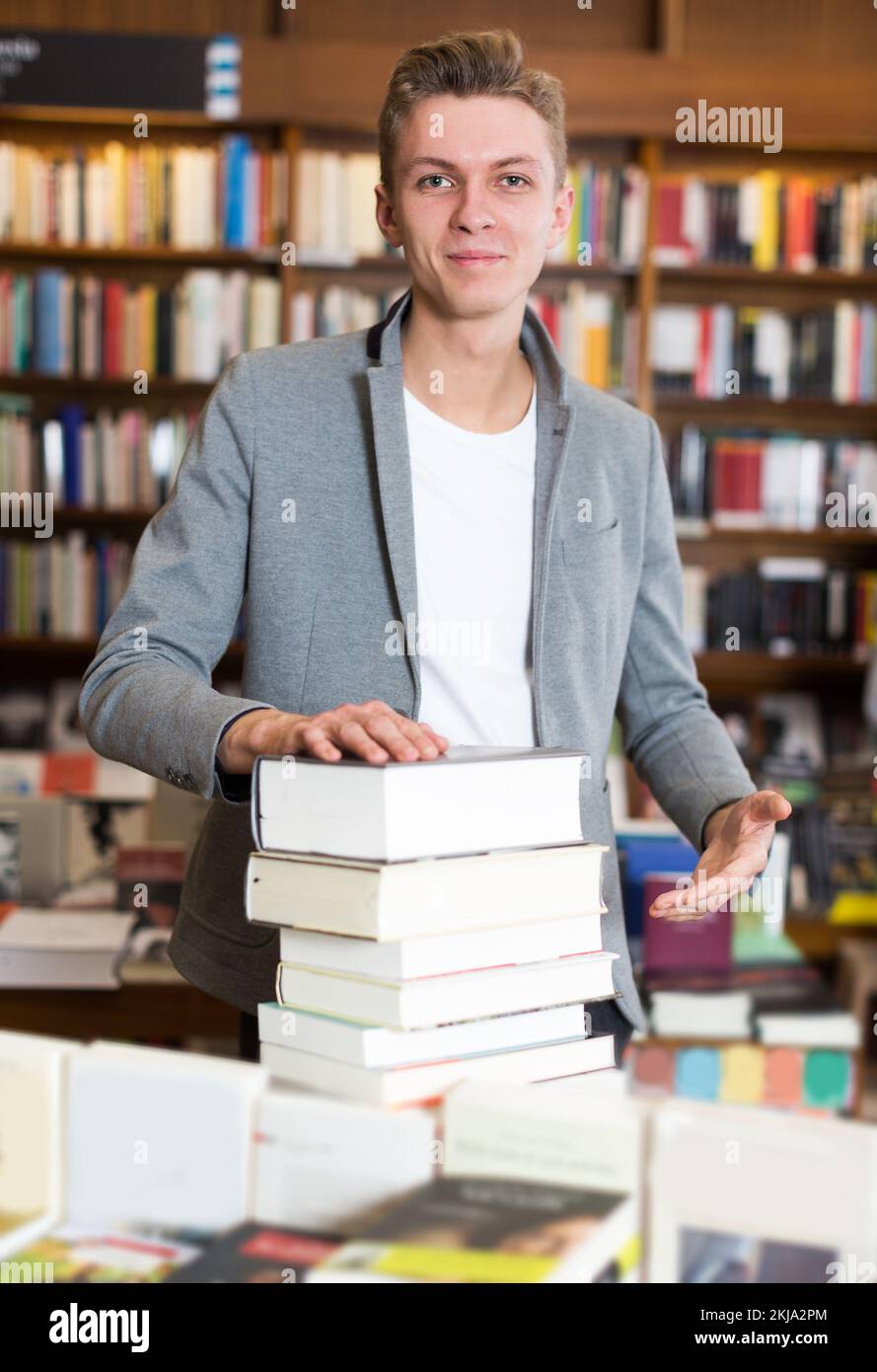 student standing in library with pile of books Stock Photo - Alamy