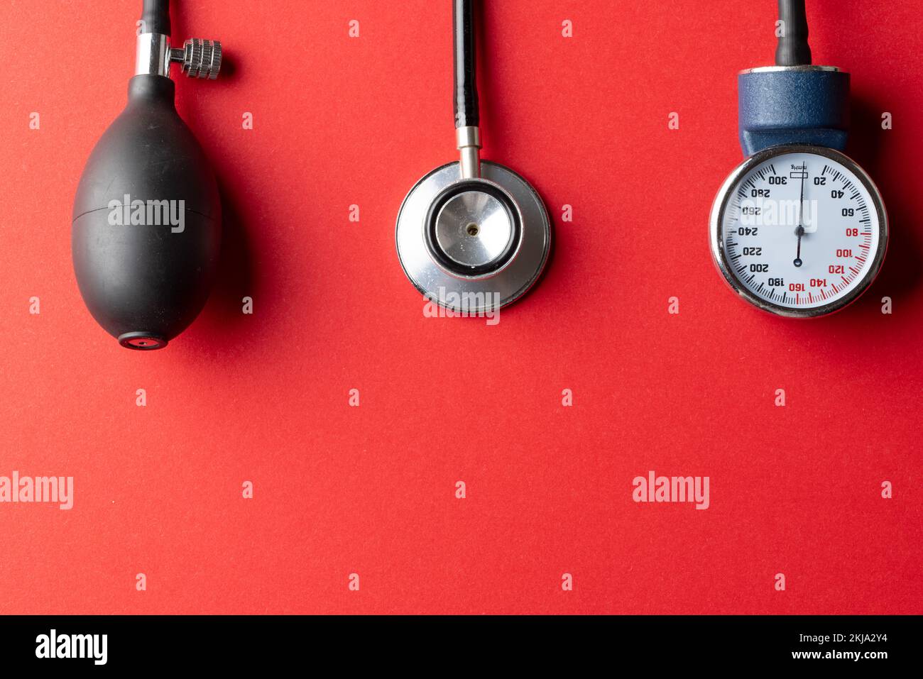 Composition of sphygmomanometer and stethoscope on red background with copy space Stock Photo