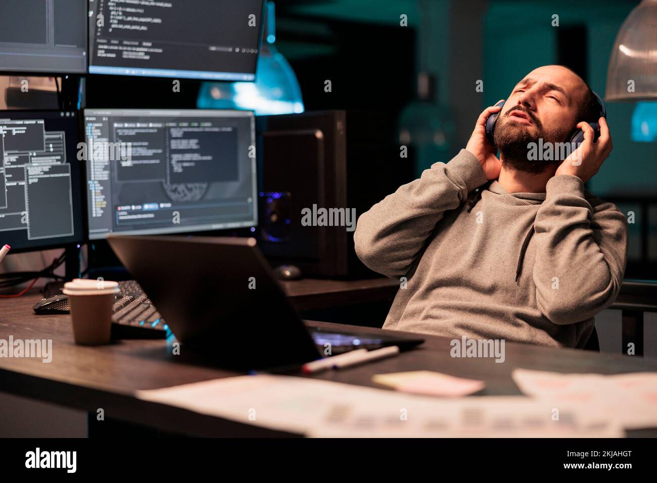 Software developer singing song in office, using multiple screens to ... image.
