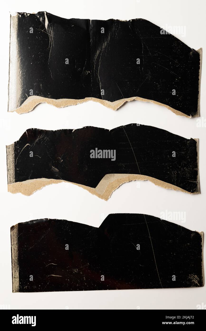 Ripped up pieces of black cardboard with copy space on white background ...