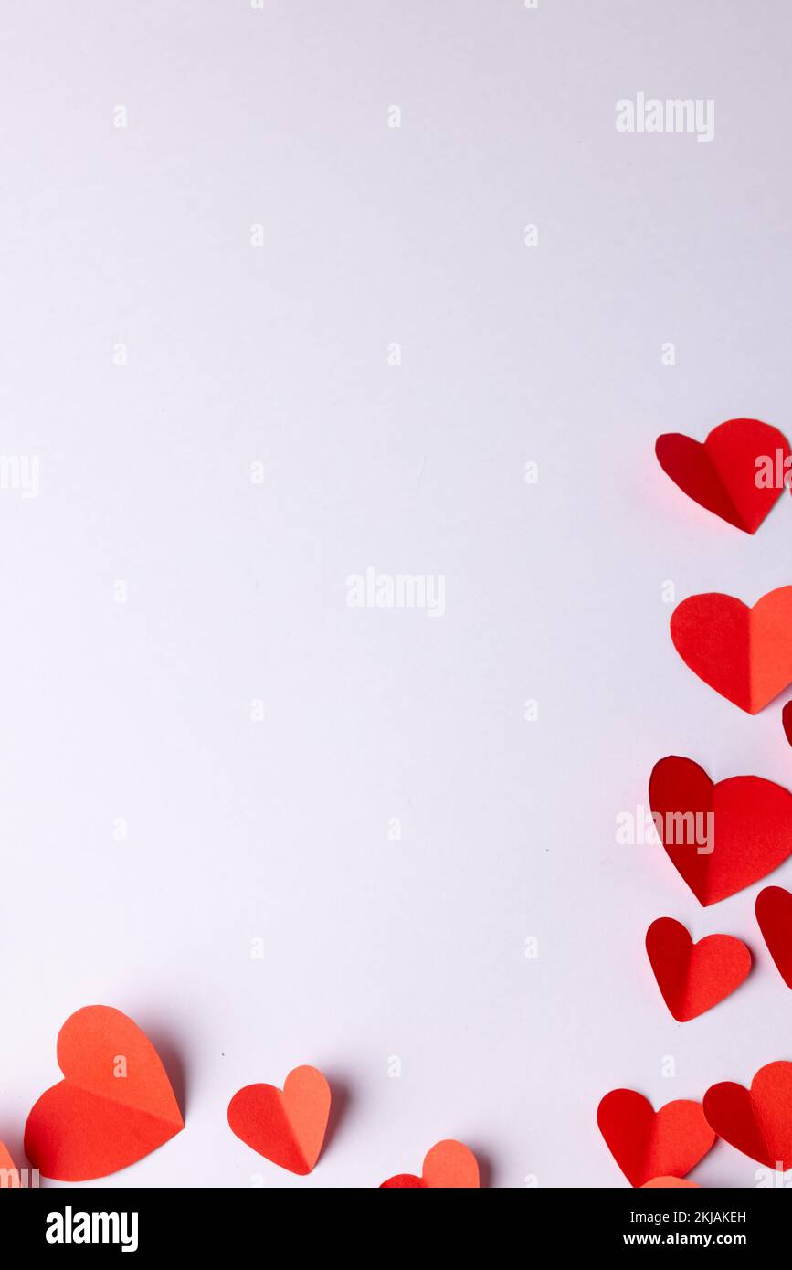 Vertical image of red paper heart shapes on white background with copy ...
