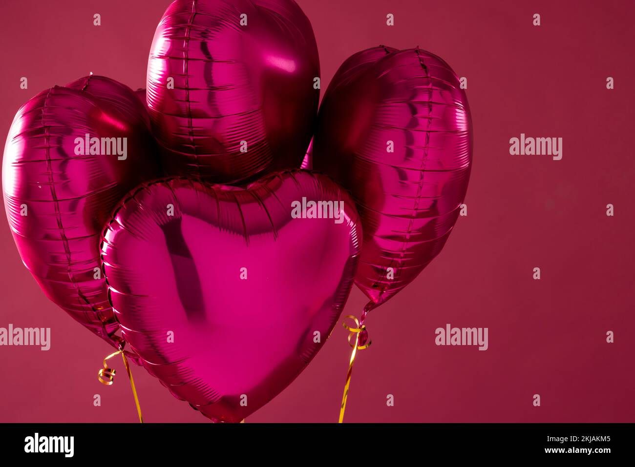 Four shiny pink heart shaped balloons floating on pink background with ...