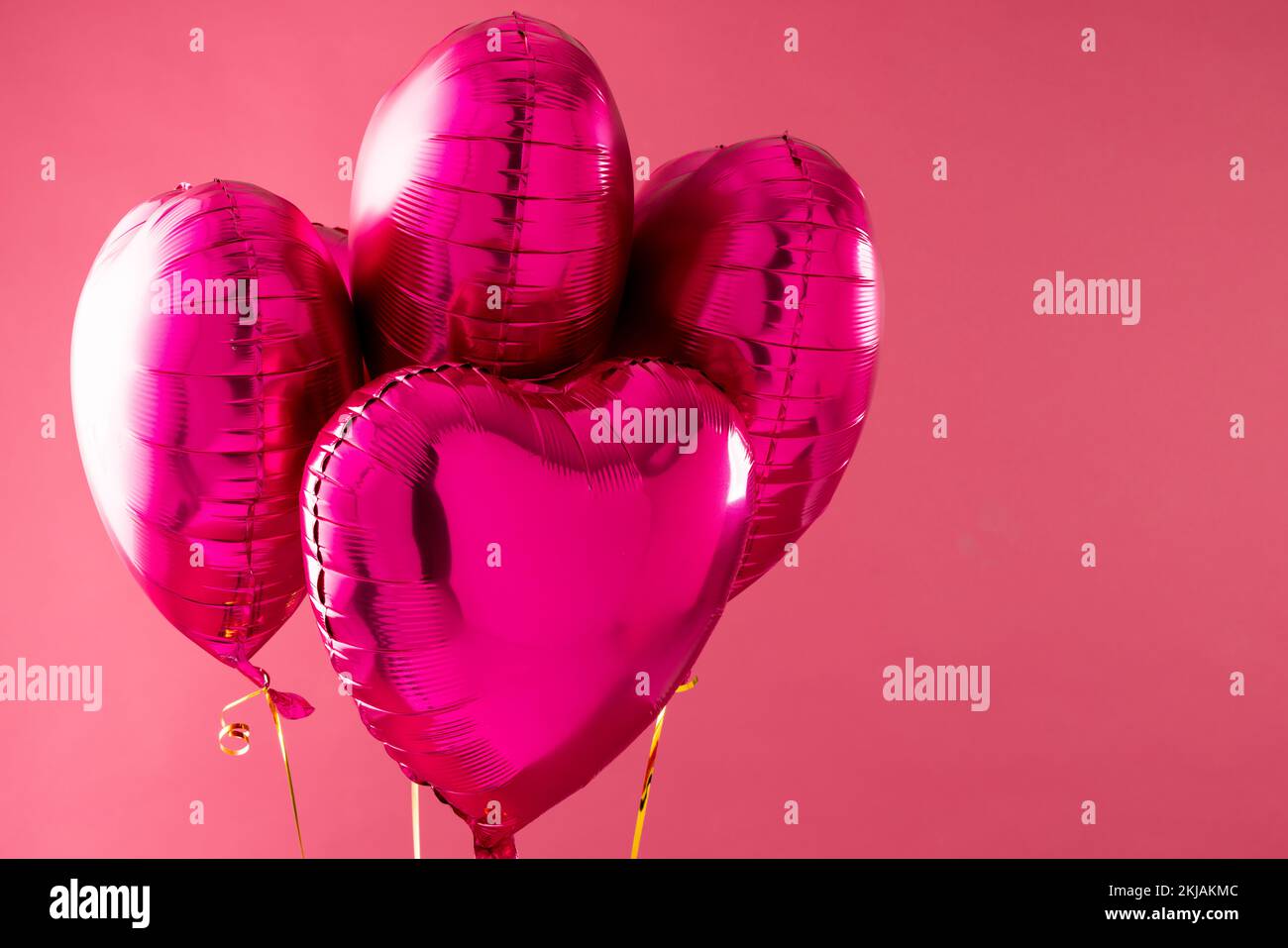 Four shiny pink heart shaped balloons floating on pink background with ...